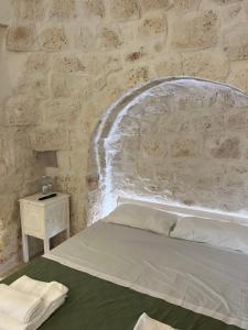 Ce lit se trouve dans un dortoir doté d'un mur en pierre. dans l'établissement Trullo Moi, à Ostuni