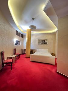 a bedroom with a white bed and a red carpet at HOTEL GJUTA in Tirana