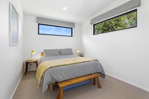 a bedroom with a bed and two windows at Hannah's Bay Hideaway in Rotorua