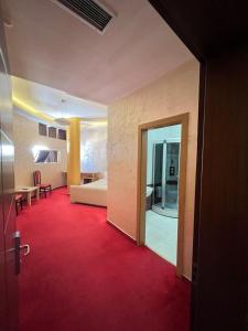 a room with a red carpet and a bedroom at HOTEL GJUTA in Tirana