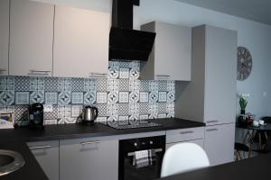 cocina con armarios blancos y encimera negra en Turkusowe tarasy apartament, en Czeladź