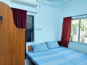 ein Schlafzimmer mit einem Bett und zwei Fenstern in der Unterkunft Chaiti Lodge - Santiniketan Bolpur in Bolpur