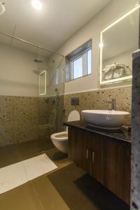e bagno con lavandino, servizi igienici e doccia in vetro. di Eerus Villa 3Bhk Luxurious Home ad Arpora