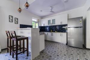 Eerus Villa 3Bhk Luxurious Home في آربورا: مطبخ مع دواليب بيضاء واجهزة ستانلس ستيل