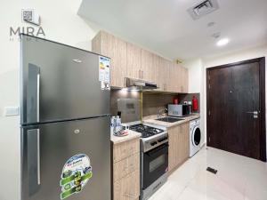 Mira Holiday Homes - Serviced apartment in Dubai Land في دبي: مطبخ مع ثلاجة ستانلس ستيل