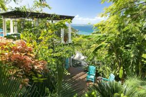 a garden with two blue chairs and the ocean at Arc Du Soleil- 3 BDRM Sleeps 6 Stunning Views in Cruz Bay