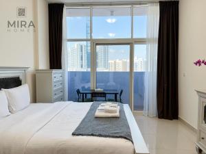 Mira Holiday Homes - Serviced apartment in Dubai Land في دبي: غرفة نوم بسرير كبير مع نافذة كبيرة