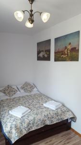 a bed in a bedroom with two pictures on the wall at APARTHOTEL "Apartamenty KORONA" w Cieplicach przy basenach Termy Cieplickie koronacieplic,pl in Jelenia Góra