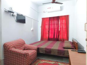 ein Schlafzimmer mit einem roten Bett und einem Stuhl in der Unterkunft Chaiti Lodge - Santiniketan Bolpur in Bolpur