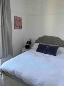 a bedroom with a large white bed with blue pillows at Flat Beside the sea in Southend-on-Sea