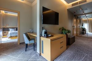 a hotel room with a desk and a tv on the wall at Avalon Resort & SPA in Miskolctapolca