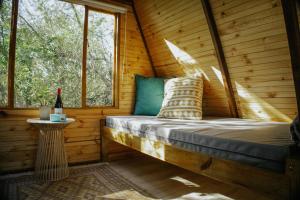 a bed in a wooden cabin with a window at Gaia A-frame cabin in Swellendam