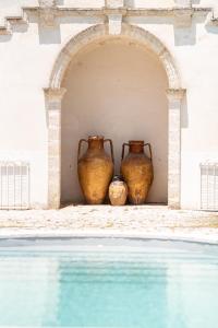 dos jarrones sentados junto a una piscina en Villa Encantamiento - Dimora Gelsomino - Masseria Storica nel cuore della Puglia con piscina, en Latiano