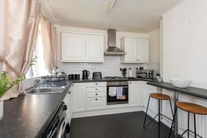 a kitchen with white cabinets and black counter tops at Broome Road in Durham