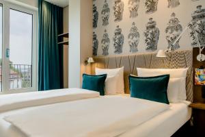 a bedroom with two beds with blue and white pillows at Motel One Dresden am Zwinger in Dresden