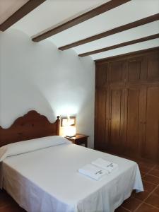 a bedroom with a white bed and a wooden cabinet at El Marqués, magnífica casa rural con piscina in Almería