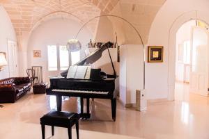 un piano negro en una sala de estar con sofá en Villa Encantamiento - Dimora Gelsomino - Masseria Storica nel cuore della Puglia con piscina, en Latiano