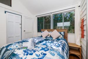 a bedroom with a blue and white bed with windows at The Forest Lodge in Mount Tamborine