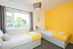 two beds in a room with yellow walls and a window at Broome Road in Durham