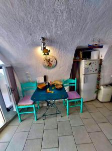 Mermaid Cave Apartment Old Port, Fira في فيرا: مطبخ مع طاولة وكرسيين وثلاجة
