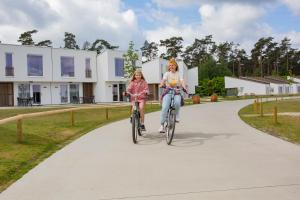 Duas raparigas a andar de bicicleta por um caminho em Park Eksel em Hechtel-Eksel