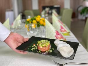 una persona sosteniendo un plato de comida en una mesa en Hotel Ponteo - Activity Park, en Bratislava