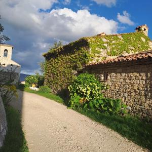 un edificio de piedra con hiedra al lado de una carretera en Les Roses Trémières, en Bargème