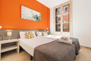 2 camas en una habitación con pared de color naranja en AB Vila i Vila Apartments, en Barcelona