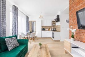 a living room with a green couch and a brick wall at Bm Apartamenty w Centrum Szczecin in Szczecin