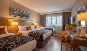 a hotel room with two beds and a desk at Clayton Hotel Liffey Valley in Clondalkin 
