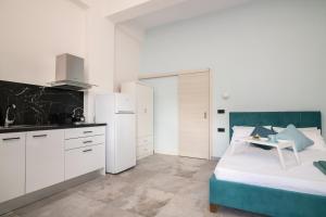 ザキントスにあるNostalgia Apartments Zanteの白いキャビネット付きのキッチン、ベッド1台が備わる客室です。