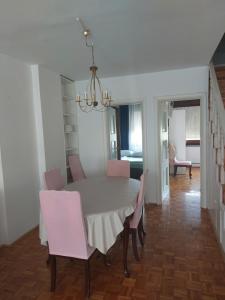 a dining room with a white table and pink chairs at Apartman LAURA in Zagreb