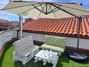 zwei Stühle und ein Regenschirm auf dem Dach in der Unterkunft Casa El Frenazo 