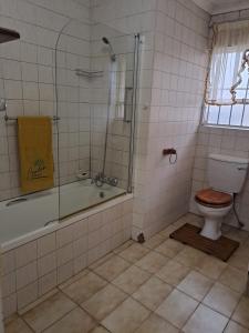a bathroom with a tub and a toilet and a shower at Beulah group House in Roodepoort