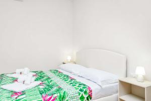 een witte slaapkamer met een bed met een groene en witte deken bij Accanto 2 in Trebiano