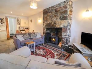 a living room with couches and a stone fireplace at Llygoden Cottage in Caernarfon