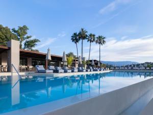 a swimming pool at a resort with palm trees at Dreams Corfu Resort & Spa - All Inclusive in Gouvia