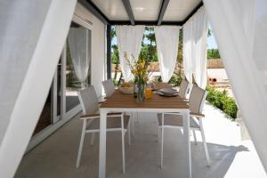 扎頓的住宿－Dionis Zaton - Camping, Glamping, Holiday Houses & Rooms，一间带木桌和白色椅子的用餐室