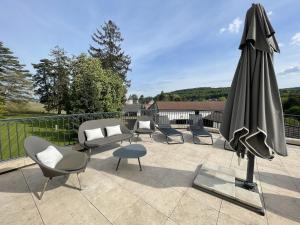 eine Terrasse mit einem Sonnenschirm, Stühlen und einem Tisch in der Unterkunft Manoir de Villamont in Savigny-lès-Beaune