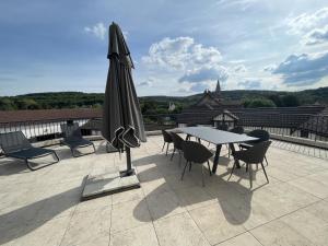 eine Terrasse mit einem Sonnenschirm, einem Tisch und Stühlen in der Unterkunft Manoir de Villamont in Savigny-lès-Beaune