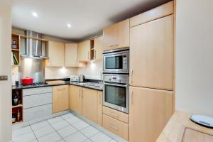 a kitchen with wooden cabinets and stainless steel appliances at Spacious 2 bed 2 bath Kings Cross Apartment in London