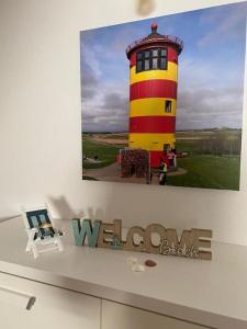 a picture of a yellow and red lighthouse on a wall at Landhaus "Alte Welt" Nordseeküste in Osteel