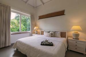 a bedroom with a large white bed with a window at Hamptons Charm by StayVista Luxury 5BR with Pool, lawn & table tennis in Alibaug