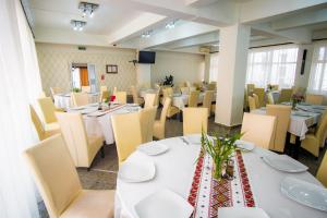 a dining room with white tables and chairs at Hotel Turist in Pucioasa