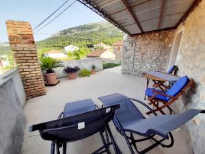eine Terrasse mit Stühlen, einem Tisch und einem Tisch in der Unterkunft Vacation House Calluna in Vrisnik