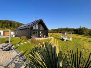 a black house with a deck and chairs in the yard at Chalet Deluxe in Freyung