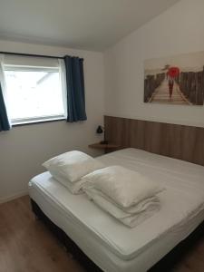 Schlafzimmer mit einem Bett mit weißer Bettwäsche und einem Fenster in der Unterkunft Domstad Resort Utrecht Vakantiewoningen in Utrecht