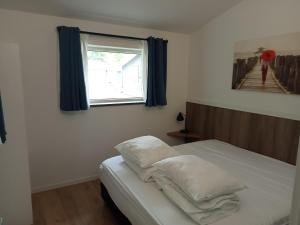 ein Schlafzimmer mit einem Bett mit weißen Kissen und einem Fenster in der Unterkunft Domstad Resort Utrecht Vakantiewoningen in Utrecht