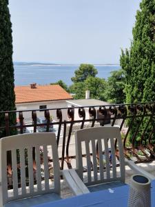 2 sillas blancas sentadas en un balcón con vistas al océano en Guesthouse Galimar, en Crikvenica
