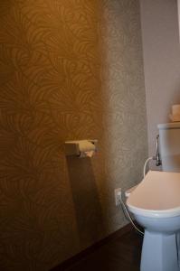 a bathroom with a toilet and a wall at Hotel Takao Asiel in Sōgayato